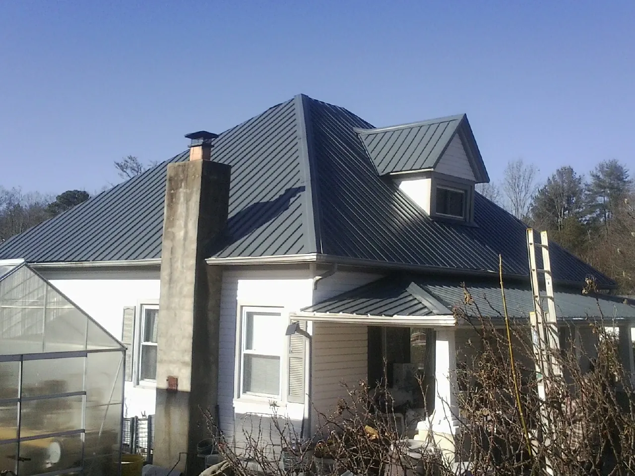 Dark blue standing seam metal roof on a white farmhouse with dormer — Slate & Tile Roof Repair by Roofing Brothers in New Milford