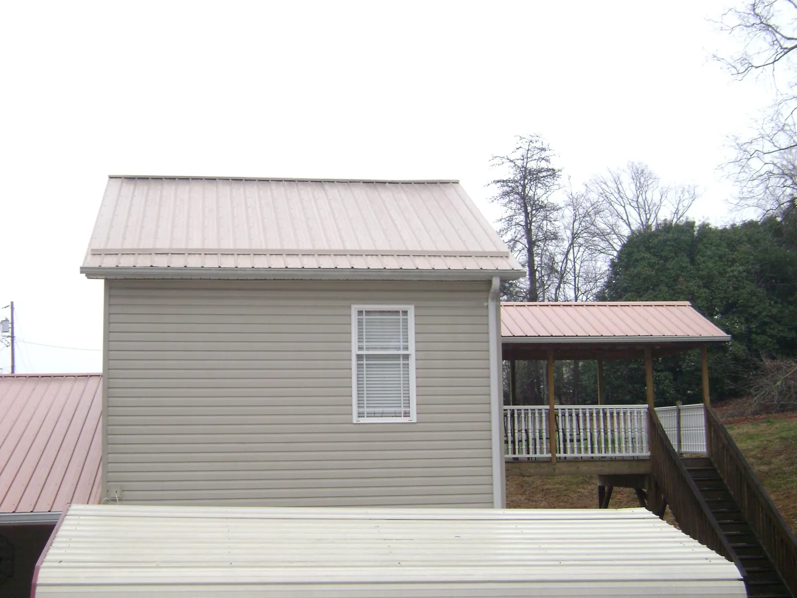 Tan metal roofs on a two story addition and attached porch, from a Roof Replacement job in New Milford
