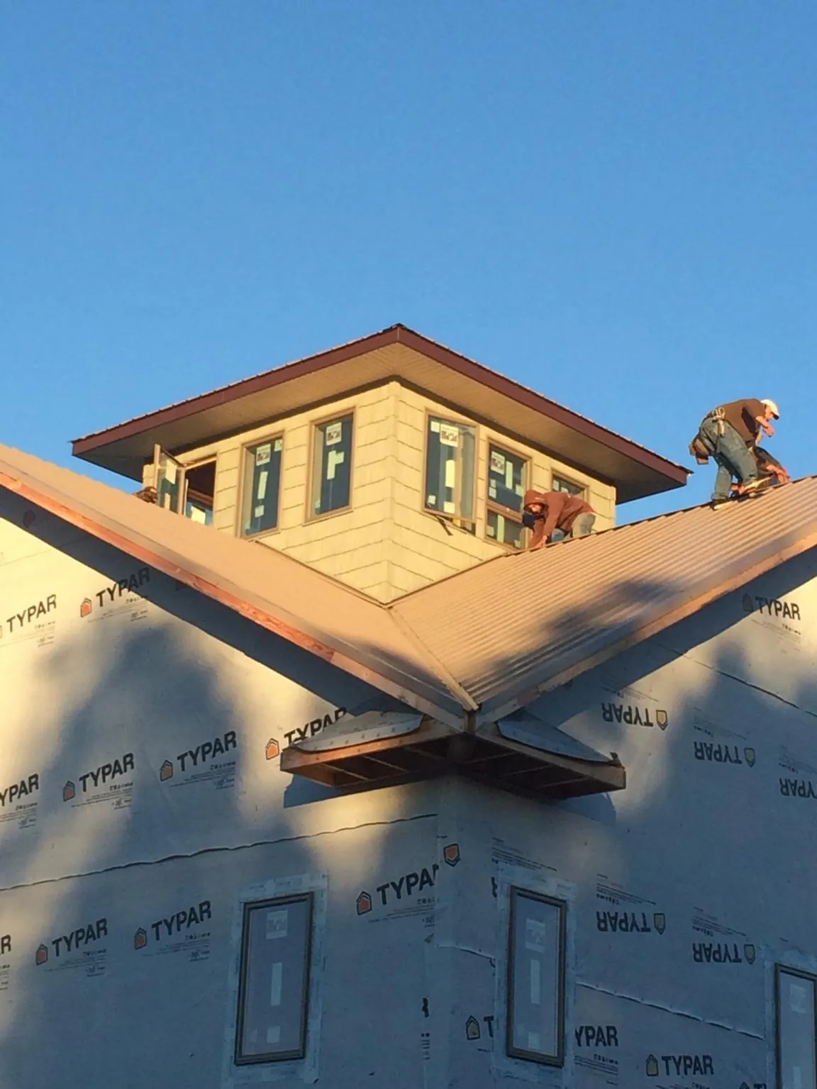 Roofers working around a rooftop cupola on a new metal roof at sunset — Roof Waterproofing in New Milford by Roofing Brothers